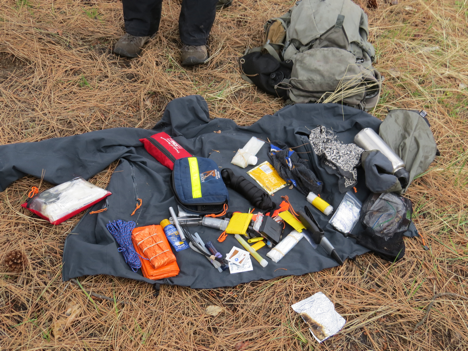 This photo shows a survival kit that an instructor has pulled apart to show the contents to students. 